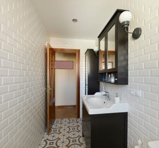 Bathroom with porcelain sink with black wooden cabinet, mirrored cabinet and white tiles on the walls