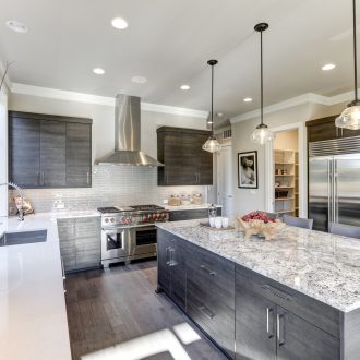 Modern gray kitchen features dark gray flat front cabinets paired with white quartz countertops and a glossy gray linear tile backsplash. Bar style kitchen island with granite counter. Northwest, USA