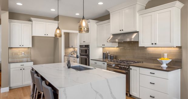 Kitchen in new luxury home with waterfall isalnd, stainless steel appliances, pendant lights, and hardwood floors